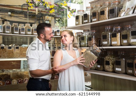 joyful young couple choosing herbs and spices in organic food store
