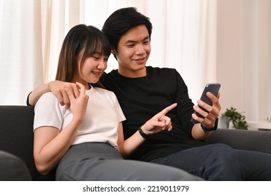 Joyful Young Couple Embracing And Shopping Online On Internet Via Smart Phone. People And Technology Concept