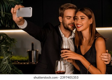 Joyful young couple taking selfie while having romantic dinner at home. Proposal for social media. Anniversary celebration and posting on Internet online in restaurant indoors - Powered by Shutterstock