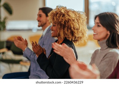 Joyful young diverse people are in audience in a business meeting clapping their hands together after presentation. - Shutterstock ID 2260436229