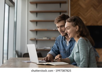 Joyful Young Family Couple Using Computer Apps, Planning Future Investments Or Web Surfing Information. Happy Millennial Generation Colleagues Working Together On Online Project In Modern Office.