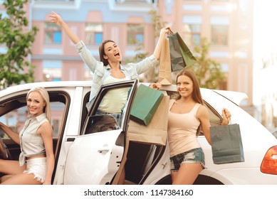 Joyful Young Girls Back with Lot of Shopping Bags and Standing by Car. Lifestyle Concept. Woman in Shopping. Female with Bags Enjoying in Shopping. Cheerful Friends in Casual Clothes.