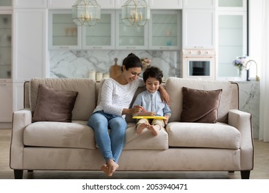 Joyful young Indian mother or nanny drawing on toy table with happy cute little preschool kid boy, improving creative skills, spending leisure weekend time together at home, custody concept.