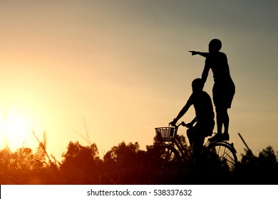 Joyful young man riding a bicycle together. Best friends having fun on a bike at the meadow.