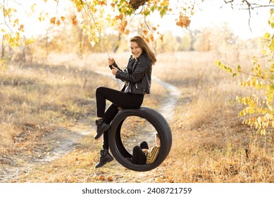 Joyful young mother having fun with her little son in nature, sitting together on a swing wheel suspended from a tree - Powered by Shutterstock