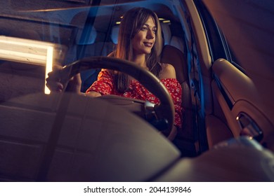 Joyful Young Woman Driving Car At Night