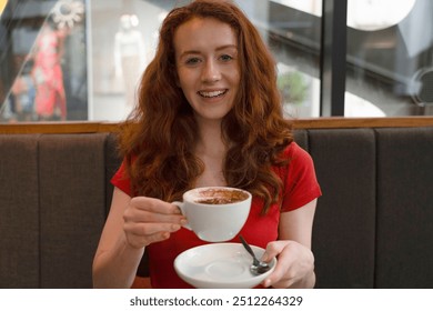 A Joyful Young Woman Enjoys a Warm Cup of Coffee at a Cozy Café During a Sunny Afternoon - Powered by Shutterstock