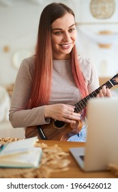 Joyful Young Woman Giving Ukulele Lesson By Zoom. Remote Learning To Play The Ukulele