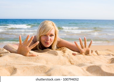 Joyful young woman lying on the sand on a summer day