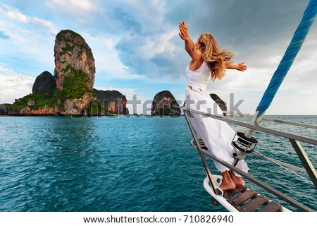 Joyful young woman portrait. Happy girl stand on board of sailing boat have fun discovering islands in tropical sea on summer coastal cruise. Travel adventure, yachting with kids on family vacation.