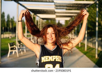 Joyful Young Woman Touching Hair In Park