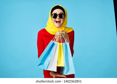  joyfully hijabs a woman in a veil with glasses holding packages colored on a blue background                              - Shutterstock ID 1402362851