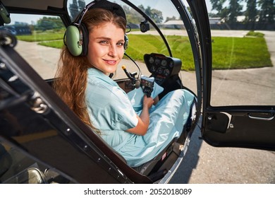 Joyous airwoman sitting in helicopter cabin before flight