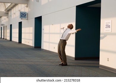 Joyous Businessman Standing Outside Meeting Room, Arms Out And Head Back, Smiling, Side View