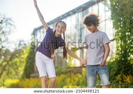 Joyous dark-haired girl learning to skateboard outdoors