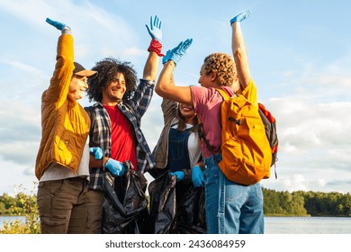 Joyous group of volunteers raising hands in triumph after a lake shore clean-up effort. Ecstatic Volunteers Celebrating a Successful Lake Cleanup. High quality photo - Powered by Shutterstock