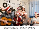 Joyous holiday gathering featuring Asian family singing and playing guitar, adorned with Christmas party decorations and festive Santa hats with joyful mood of reunion at home