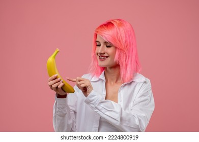 Joyous pink-haired girl pretending to call on a fruit phone - Shutterstock ID 2224800919