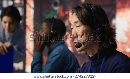 Joyous technical support senior agent in call center office doing troubleshooting. Jolly experienced Asian IT worker fixing customer connectivity issues using computer, camera A