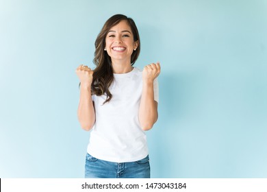 Joyous woman clenching fist while celebrating against isolated background - Shutterstock ID 1473043184