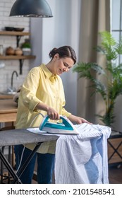Joyous woman ironing wrinkled clothes on the ironing-board