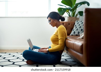 The joys of working from home. Cropped shot of an attractive young woman sitting crosslegged on the floor and using her laptop at home.