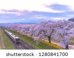JR Tohoku train railroad track with row of full bloom cherry tree along the Shiroishi river ( Shiroishigawa tsutsumi Hitome Senbonzakura ) with mountain background in Funaoka Castle Park,Miyagi, Japan