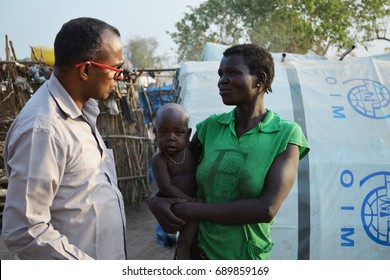 Juba, South Sudan, February 2017. Salesian Priest Talking To A Sad Woman With A Baby. Camp For Internally Displaced Persons (IDPs). Captured During Civil War.