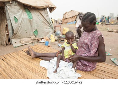 JUBA, SOUTH SUDAN - FEBRUARY 28 2012: Unidentified Woman With Her Daughter Sits In Front Of Her Hovel In Displaced Persons Camp, Juba, South Sudan. Refugees Stay In Harsh Conditions In Camps Of Juba.