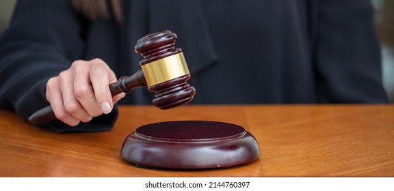 Judge Female Hand Holding A Gavel On Wooden Law Court Bench, Close Up Above View. Justice And Punishment Concept