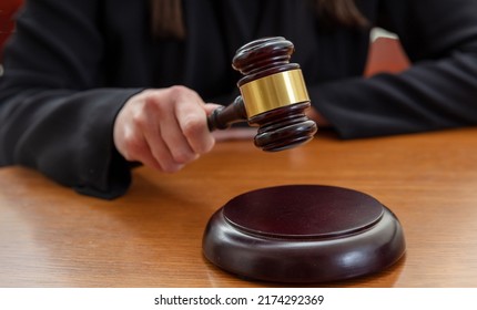 Judge Female Hand Holding A Prosecution Gavel On Wooden Law Court Bench, Close Up Front View. Justice And Punishment Concept