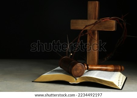 Judge gavel, bible, wooden cross and crown of thorns on grey table. Space for text