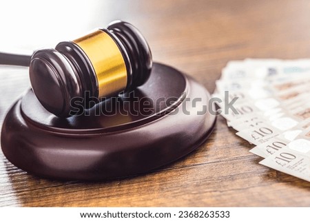 Judge gavel and british pound sterling on the wooden table.