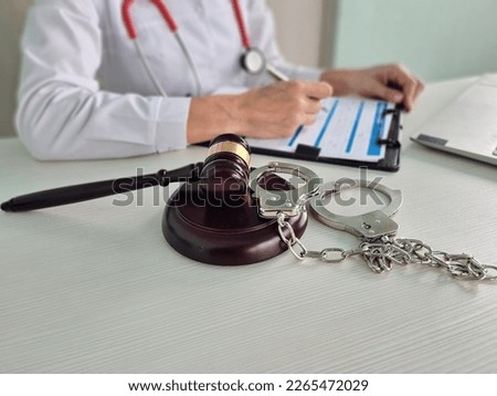 Judge gavel handcuffed doctor dealing with insurance paperwork in medical clinic. Litigation in medicine
