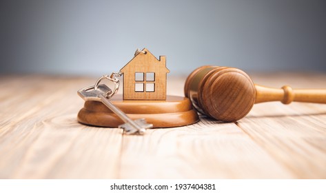 Judge gavel and house key on wooden background. Estate law concept