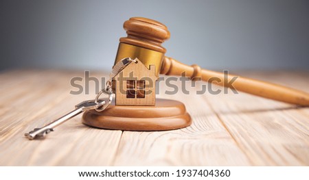 Judge gavel and house key on wooden background. Estate law concept

