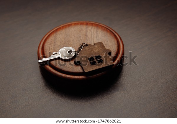 Judge gavel and key chain in shape of two splitted\
part of house on wooden background. Concept of real estate auction\
or dividing house when divorce, division of property, real estate,\
law system