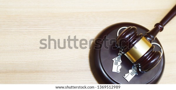 Judge gavel and key ring in shape of two\
splitted part of house on wooden background. Concept of real estate\
auction or dividing house when divorce, division of property and\
real estate, law\
system.\
