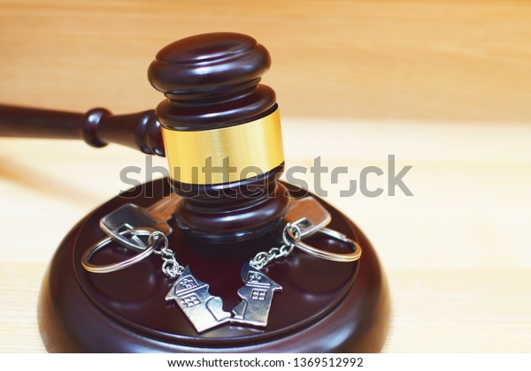 Judge gavel and key ring in shape of two\
splitted part of house on wooden background. Concept of real estate\
auction or dividing house when divorce, division of property and\
real estate, law\
system.\

