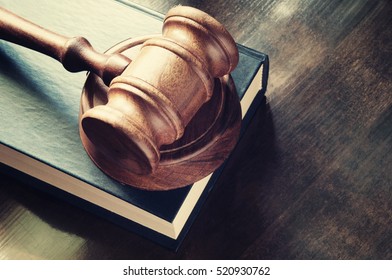 Judge gavel and legal book on wooden table close up