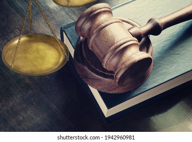 Judge gavel on legal book and brass scale on wooden table, justice and law concept