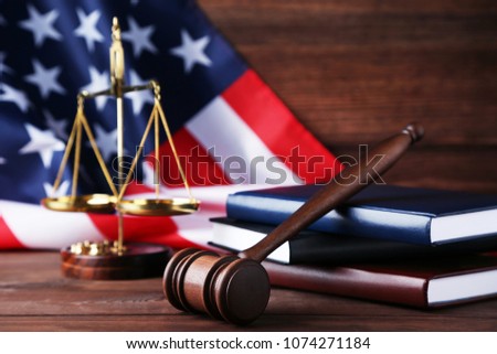 Judge gavel with scales, books and american flag on wooden table