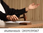 Judge striking mallet at wooden table indoors, closeup. Space for text
