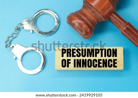 judge's gavel, iron handcuffs and wood with the word presumption of innocence. concept of guilt and court