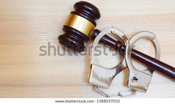 Judges gavel or law mallet and handcuffs on\
wooden background. Judgement, legal system, time for justice,\
bribery and corruption problems\
concept.\
