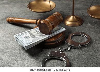Martillo del juez, dinero, esposas y balanzas de justicia en la mesa gris