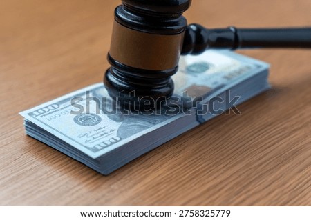 A judge's gavel on a stack of one hundred dollar bills. Legal fees, court settlements, judicial corruption, bail, and the high cost of litigation concept.