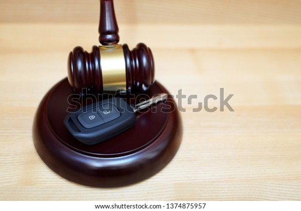 Judges gavel, sounding block\
and car key on light wooden background with copy space. Car\
auction, legal trial of traffic accident, traffic law and justice\
concept.\

