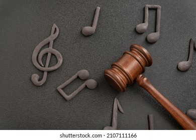 Judges gavel surrounded by treble clef and notes on black background. Violation of music license and copyright. Music piracy