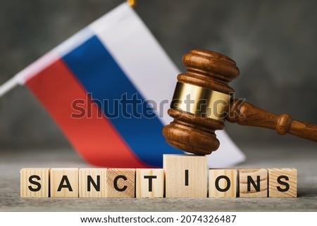 judge's gavel, wooden cubes with the text on the background of the Russian flag, the concept on the topic of sanctions in Russia